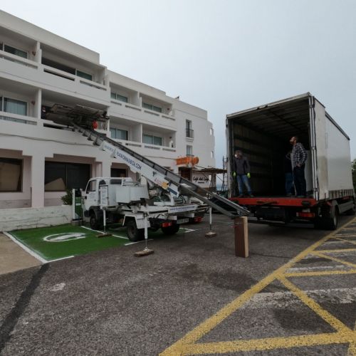 Vista amplia de la plataforma elevadora en posición junto al camión de mudanzas de Plataformas Ibiza